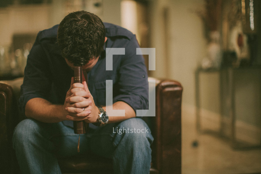 Man clutching Bible and praying