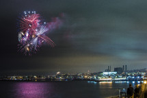 Fireworks over the water by city skyline