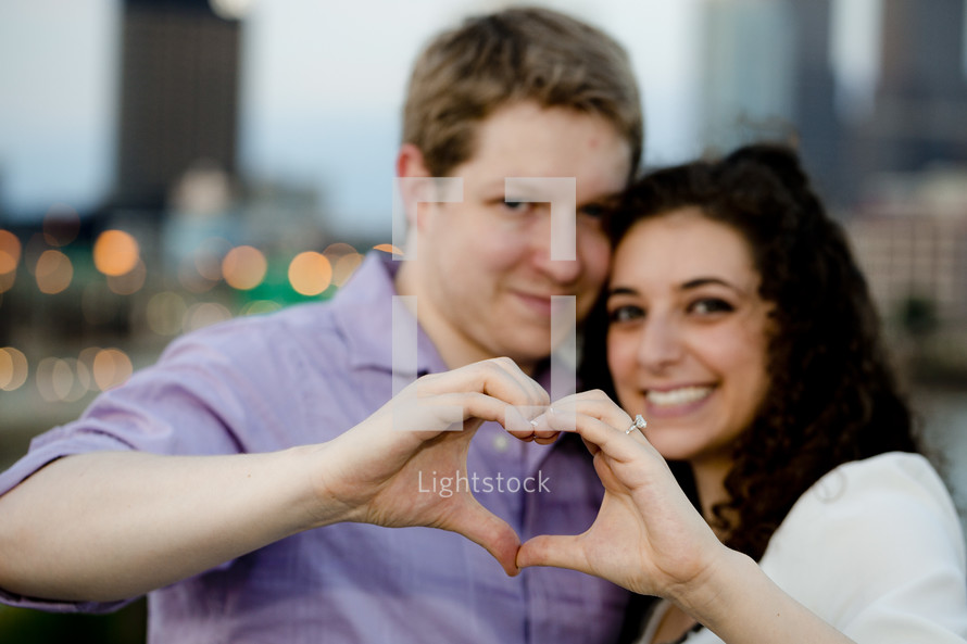 Happy couple making heart shape with hands