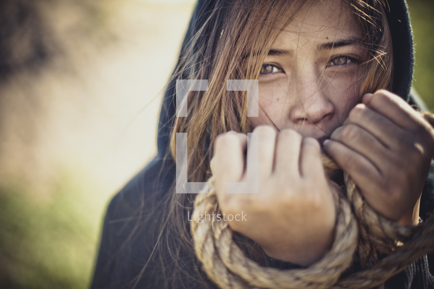 girl with her hands tied in rope 