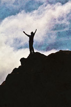 man with arms raised in worship to God on top of a mountain
