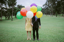 couple holding helium balloons 