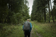 Man with backpack hiking through forest path