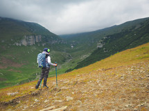 Little boy with backpack hiking in scenic mountains