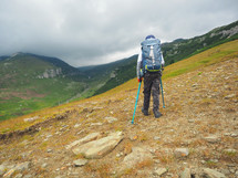 Little boy with backpack hiking in scenic mountains