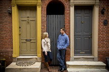 Woman and man standing between two doorways.