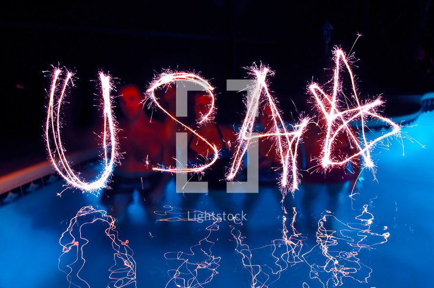 People spelling USA with sparklers. 4th July, independence day celebrations. 
