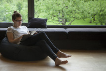 a woman sitting in a beanbag reading a Bible 
