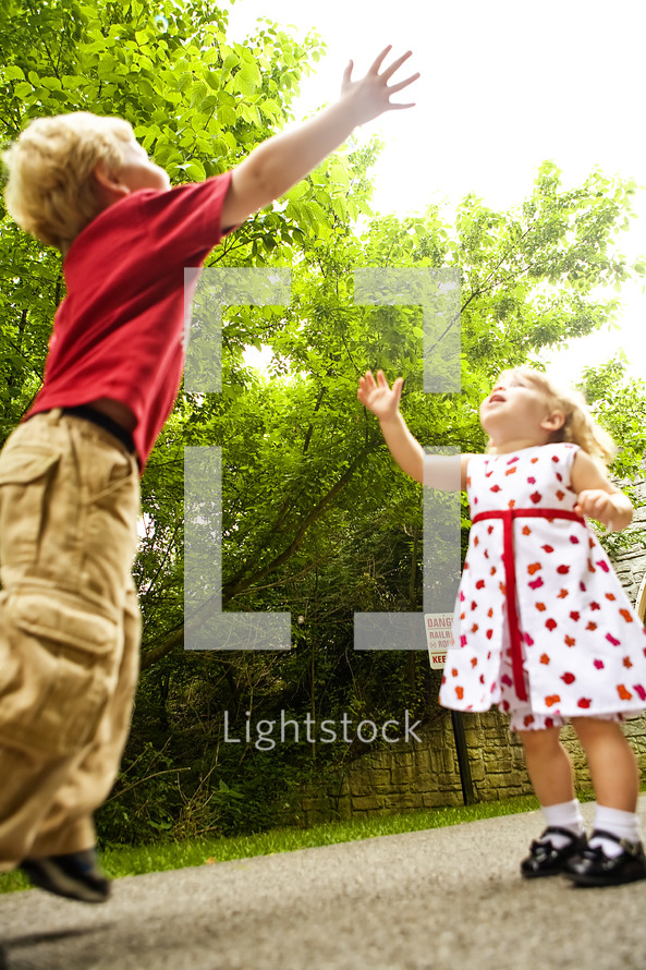 toddler boy and girl reaching for the sky