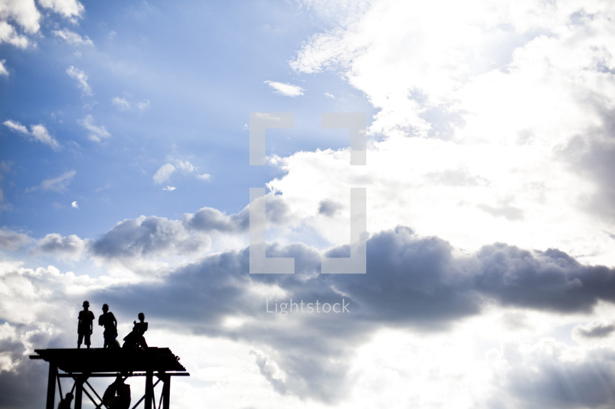 boys standing on a roof under a blue sky