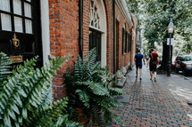 people walking down a brick sidewalk 