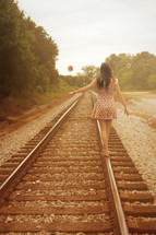 woman walking down railroad tracks