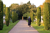 shrouded woman walking down a garden path