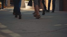 legs of people walking on a sidewalk 