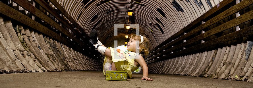 silly toddler girl playing in a tunnel