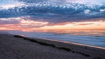 Beautiful colors of sky at sunset in ocean beach in New Zealand wild nature landscape Time lapse