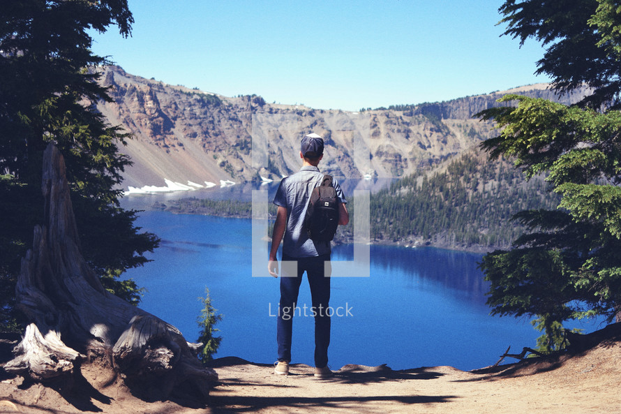 young man looking out at a lake and mountains 