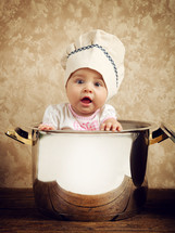 baby chef in a huge cauldron on wooden table