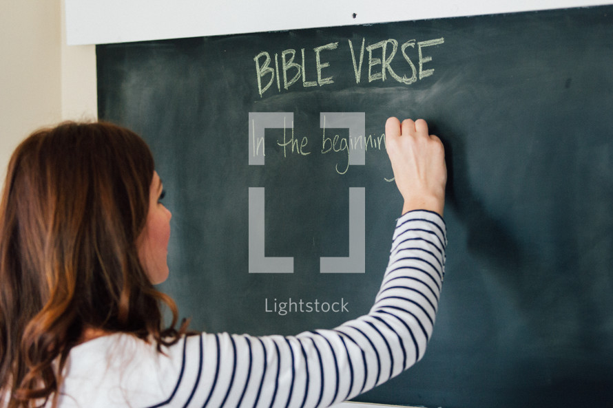 A woman writing a Bible verse on a chalkboard 