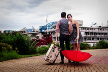 a couple with a trunk and red umbrella 