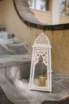 candle in a lantern on steps with tulle 