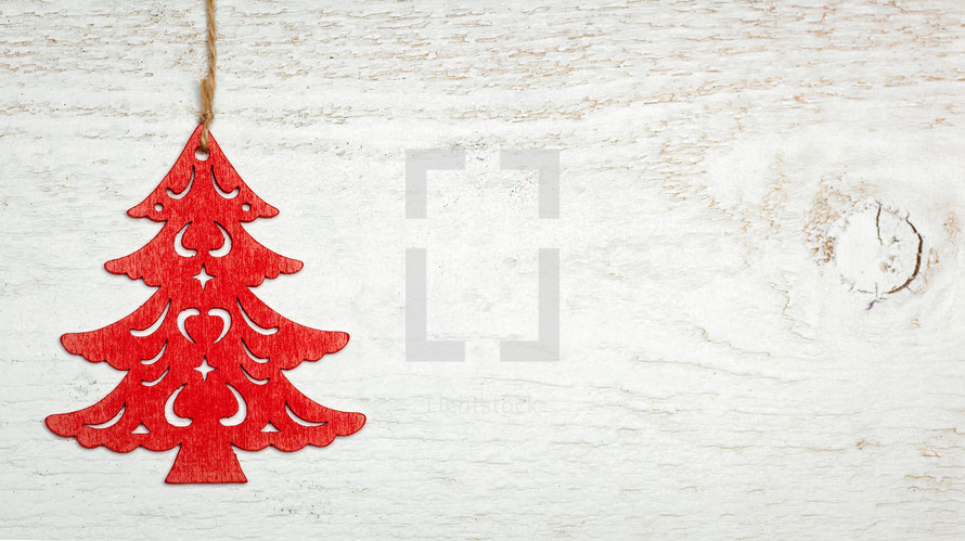 Red wooden Christmas sapling on white wood background. Decentralized object with space for text.