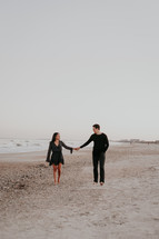 couple holding hands on a beach 