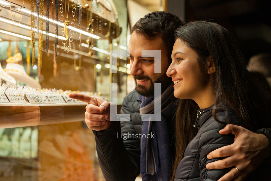 young couple choosing wedding rings while smiling while doing shopping in Florence.