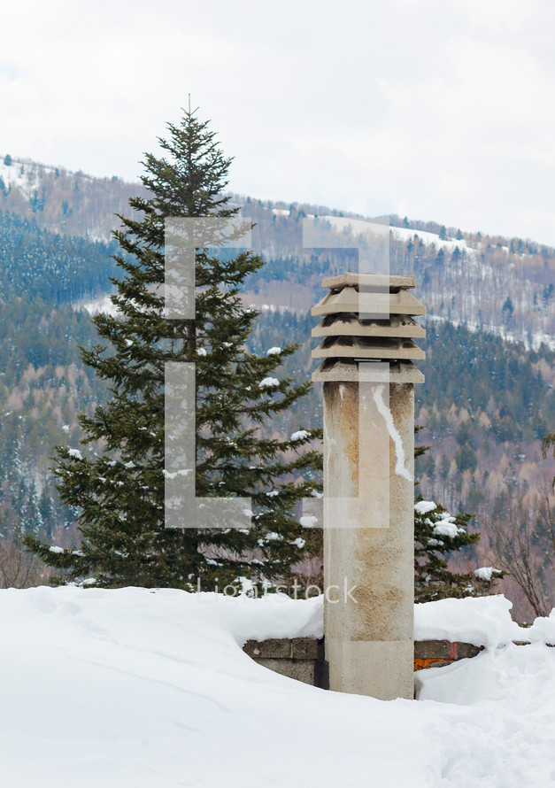 Spruce and chimney covered with snow in the tourist resort of Abetone in Italy.