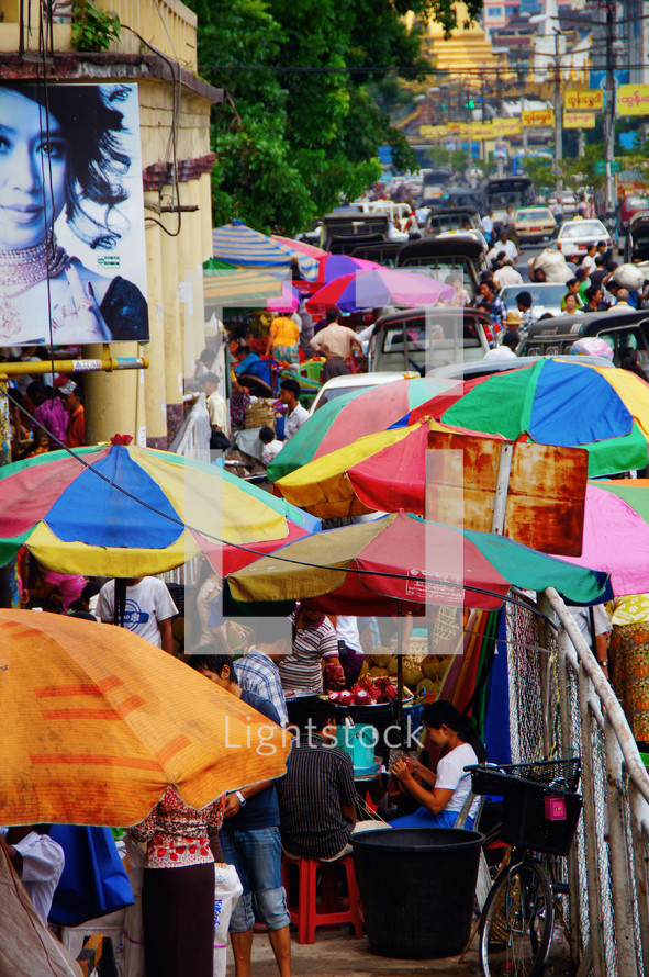 Colored umbrellas on a busy sidewalk during market day