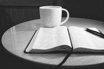 Open bible next to coffee mug