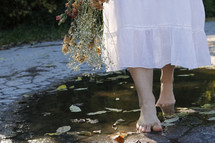barefoot woman walking beside a puddle 