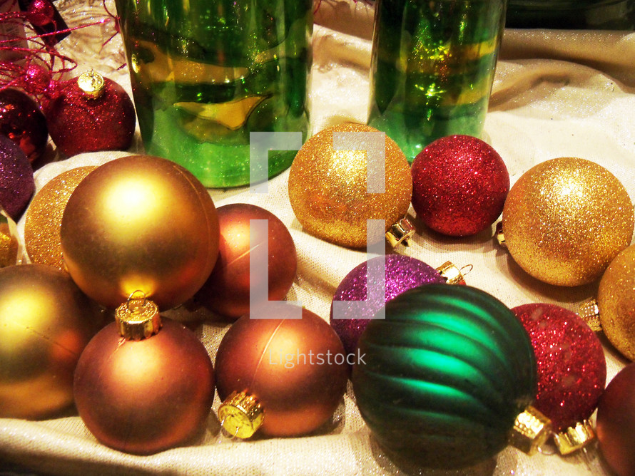 Gold, red and green Christmas ornaments decorate a window with colorful ornaments to add some Christmas cheer to the night air letting everyone in sight that Christmas time is here. 