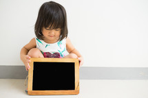 a little girl holding a chalkboard 