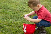 a toddler putting Easter eggs in a basket 