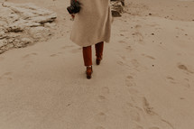 a woman walking on a beach in shoes 