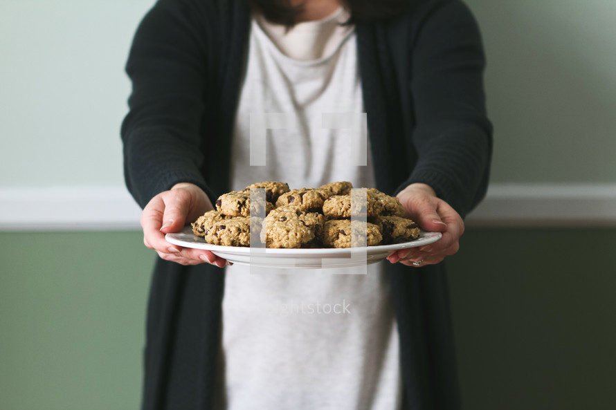 a woman presenting a plate of cookies 