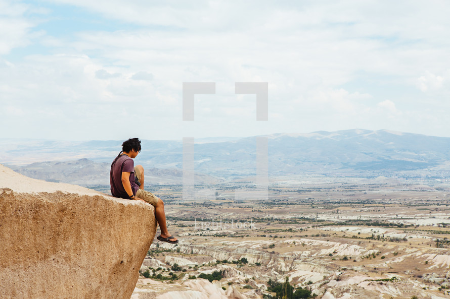 a man sitting at the edge of a cliff in Cappadocia