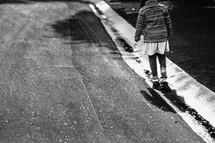 a little girl walking in puddles along the curb 