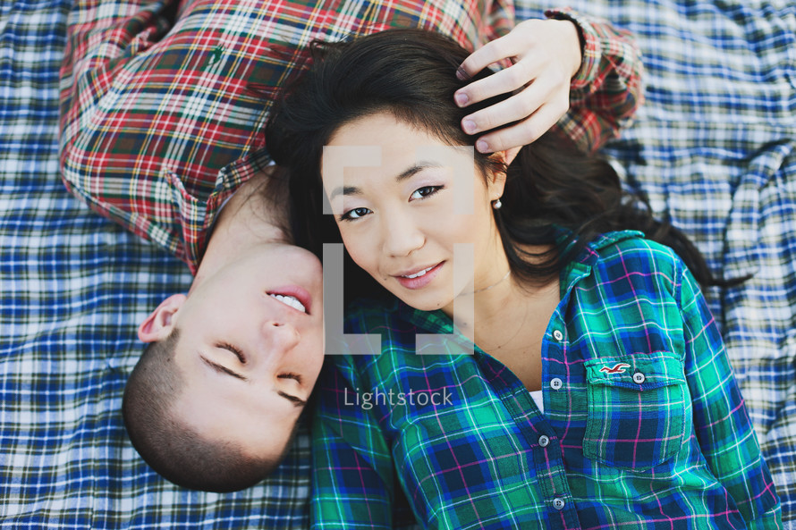 couple lying together on a plaid blanket