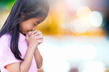 a girl with head bowed praying 