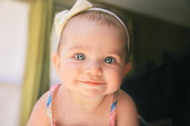 Smiling baby with a bow in her hair.