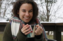 a woman holding a mug outdoors 