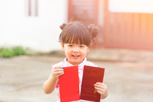 Happy Little asian girl in chinese traditional dress smiling and holding red envelope.Happy chinese new year concept.