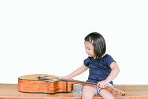 a toddler girl examining a guitar 