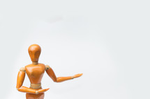 Wooden figure pose raising arm hand to introduce product for business