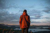 a man in a jacket looking out at mountains 