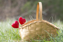 Red hearts on sticks in a basket sitting in grass
