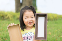 a toddler girl holding an empty box 