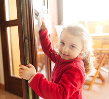 Three year old girl helps with housekeeping by cleaning the window